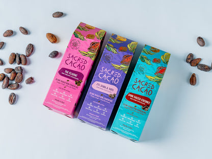 Three different coloured boxes of cacao chocolate with cacao beans scattered around.